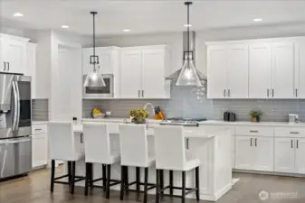 A designer - inspired kitchen featuring quartz surfaces, classic tile subway backsplash and statement modern pendants-crafted for elevated living and entertaining.