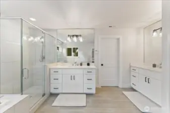 The split vanities with quartz counters in the Primary Bathroom features mirrors extending from counter to ceiling designer lighting and elegant oblong tile flooring.
