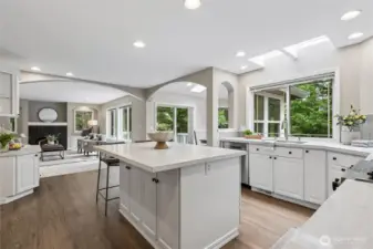 The gourmet kitchen has been beautifully updated with abundant white cabinetry, gleaming quartz countertops with a stylish tile backsplash. A stainless steel sink with a pull-out faucet adds both functionality and modern appeal under skylights and overlooks backyard through a large picture window.