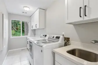 The laundry room features a tile floor and all-new cabinetry, including a spacious folding countertop. A deep utility sink with pull-out faucet, a ironing board cabinet and included washer and gas dryer are added benefits of the home. There is even a laundry chute from the second floor that drops to this room.
