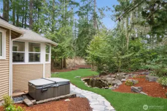 The flagstone path continues across the backyard by a fully serviced, operational hot tub, a tranquil pond and continues around to...