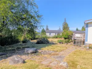 Yard with pathway to the front door and stone seating area.