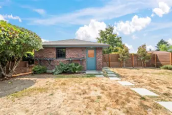Paver walkway leads to a spacious 2-car garage, with additional parking available behind the fenced area.