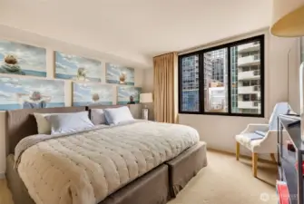 Second bedroom shown with king size bed also has double windows, wool carpet, and closet with built-in shelving and drawers.