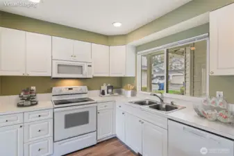 The kitchen. Double sink, dishwasher, refrigerator (just to the right, out of picture), range and oven, built in microwave. Window looks out to the front of the building, covered entry is just on the other side of the window.