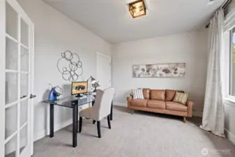 Elegant glass French doors open to a versatile space; ideal for office or fourth bedroom.