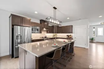 Gourmet kitchen, with elegant under-cabinet lighting, boasts premium range, expansive island with seating and sophisticated finishes thoughtfully blending style and function.
