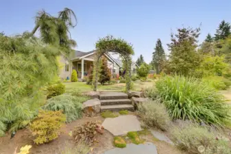 A picturesque natural archway opens to secondary wood-burning fire pit enhancing the beauty of this immaculate, park-like 1+ acre oasis.