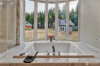 Indulge in the Bains Ultra deep soaking tub with air jets, perfectly positioned for serene forest views and ultimate relaxation