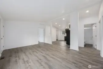 This living room nails the balance between warm and cool, starting with the grey-toned laminate flooring that reads like ashy brown wood and works with just about any style. It plays nicely with both warm and cool palettes, which is exactly what you want when decorating without committing to a trend you’ll regret later. Creamy white walls keep the space light without drifting yellow, while the crisp white trim adds contrast that feels clean and current. Add in the vaulted ceiling and open sightlines to the kitchen and dining area, and the room feels spacious, modern, and easy to live in.