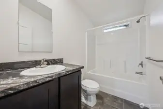 This main full bathroom in located next to bedrooms #2 & #3 and balances smart finishes with clean design. The tub surround mimics white tile with a textured surface that’s easy to maintain and surprisingly polished. Formica counters get a quiet win here, durable, budget-smart, and resistant to everyday wear, which means less worrying and more living. Stone-look vinyl floors handle moisture like a pro, brushed nickel hardware keeps things timeless, and the vaulted ceiling with a high privacy window brings in light without sacrificing discretion. Functional, fresh, and very low drama.