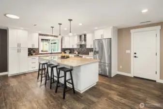 A stunning kitchen remodel with shaker cabinets, quiet-close drawers and pull-outs, granite countertops, stainless steel appliances, and a large eating island. GE dual oven and KitchenAid refrigerator.