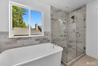 Primary bathroom with seamless glass and upgraded tile, with soaking tub.