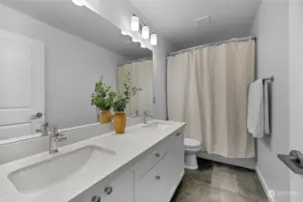 Guest bathroom with double vanity, quartz counter tops and tile flooring.