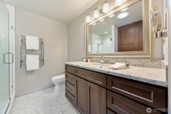The spa-like Primary Suite bath features granite countertops, extended counter space, and Shaker-style cabinets for a clean, timeless look. Ceramic tile flooring, updated fixtures, and a sleek glass shower add to the serene and functional design.