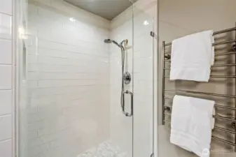 Step into a spa-like experience with this frameless, glass-enclosed walk-in shower, featuring sleek subway tile, a mosaic tile floor, and built-in niche storage for everyday ease.  Enjoy the everyday luxury of a heated towel warmer, perfectly complementing the Primary Suite’s elevated design.