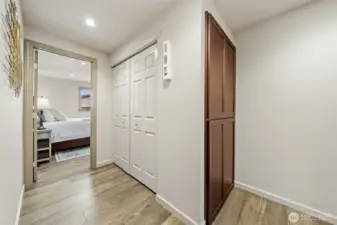 This central hallway provides seamless access to the primary suite and is thoughtfully designed with generous storage and a tucked-away washer and dryer for added convenience.