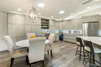 The dining area is anchored by a striking chandelier and enhanced by Solatube® lighting, bringing both elegance and natural brightness to the open layout. A built-in GE Café beverage cooler adds style and convenience for effortless entertaining.