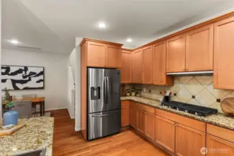 A spacious French door refrigerator (new in 2022) features a bottom freezer, built-in ice maker, and a water and ice dispenser. A sleek five-burner gas cooktop (new 2025) is set into beautiful granite counters—perfect for both daily meals and entertaining.