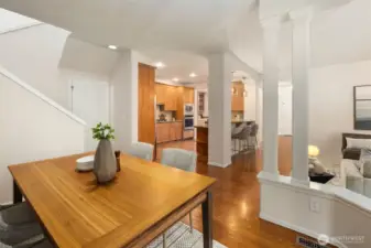 This view from the dining area highlights the home's open-concept design, rich hardwood floors, and elegant architectural touches like column accents and arched openings. Thoughtfully designed for both comfort and connection, the layout balances openness with a sense of defined space—while graceful details add a timeless touch of classic elegance and quiet dignity throughout.