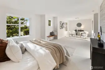 The spacious primary suite is a true retreat, featuring plush new carpeting, generous natural light from multiple windows, and a serene sitting area perfect for reading, relaxing, or morning coffee.