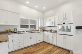 Chef's kitchen with lots of cabinets and counter space, granite counters, and white on white appliances.