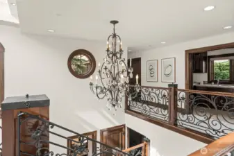 Striking grand entry featuring a dramatic chandelier, custom wrought-iron railings, and refined architectural detailing.