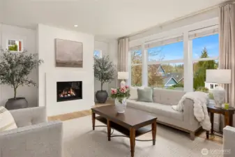A sun-filled living room with a propane fireplace and quartz surround.   Note the stunning premium grade oak flooring on the main level and upper bedroom level.