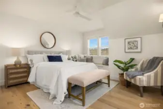 At the top of a soft wool-carpeted stairway, you'll find the Primary Suite to the right with a built-in storage bench, ceiling fan, and warm oak flooring.