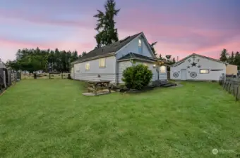 A view of the side yard. The very front of the dog kennels can be seen to the left. The shop to the right has been used as a dog grooming business.