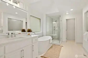 Updated primary bathroom with large format designer tile floor and separate quartz vanities with intricate millwork.