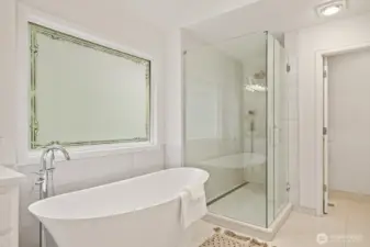 And large tiled shower with rain shower head, hand held shower head and seamless glass enclosure.