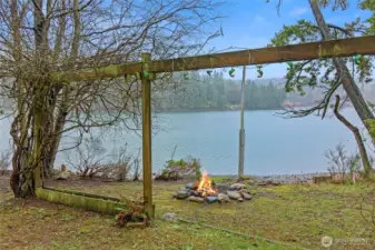 Old vines over an arbor show case the stone fire pit at the beach.