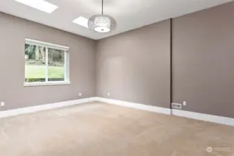 Main floor large primary bedroom with 2 skylights and a large bedroom window looking out onto the forest land