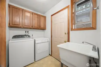 The back porch/laundry room has a deep laundry sink and opens out to the carport and storage room.