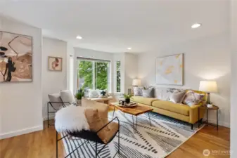Oak hardwood floors, bay window, and tons of natural light make this living space feel like a standalone house