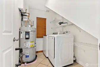 Newly installed water heater (2025) in laundry room with additional storage space