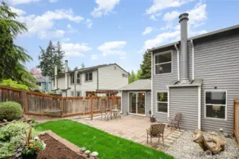 Serene backyard with large patio, grassy area and beautiful landscaping.