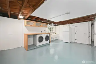 The largely clean but unfinished lower level, epoxy painted floors, a built in laundry counter made from reclaimed bowling alley material and features  tilt-up awing storage cabinets above.   A large laundry sink and second refrigerator comes with the home. Direct level access to the back yard with a large exterior awing above, is located to the left of the laundry.