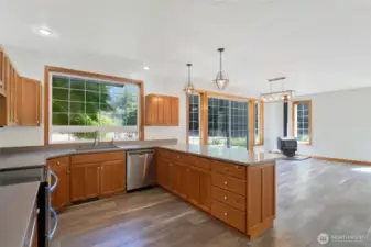 Open-concept kitchen and dining area with stunning backyard views. Features expansive island, quartz countertops, pendant lighting, and direct access to the backyard through large sliding glass doors.