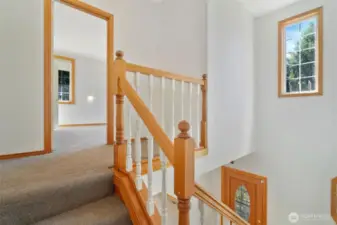 Light-filled upper landing with traditional banister and view into one of the upper-level bedrooms. A great transition space between upstairs rooms.
