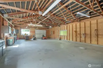 Massive detached shop with concrete floors, exposed beam ceiling, roll-up door, and built-in workbenches. Ideal for hobbies, equipment storage, or a home business setup.