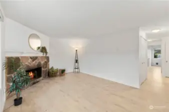 Large living space with cozy, woodburning corner fireplace.