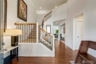 Step inside to a light-filled foyer with soaring ceilings, elegant iron-spindle staircase, and gleaming hardwood floors. The open layout creates an immediate sense of space and warmth while offering a clear view toward the office and main living areas.