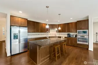 Spacious and efficient, this kitchen is designed for everyday cooking and hosting. Stainless steel refrigerator and double ovens complement the espresso cabinetry and granite surfaces, while the island seating invites connection at the heart of the home.