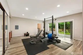 Another view of the lower level shows the fitness space opening to a private backyard patio through glass doors. This bright, open area can double as an ADU living room, yoga studio, or workout retreat with seamless indoor-outdoor flow.