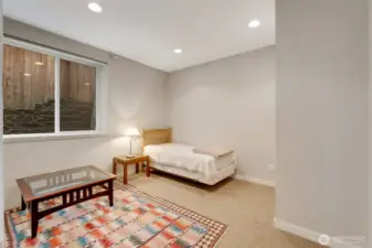 Comfortable lower-level bedroom featuring neutral tones, recessed lighting, and a large window that keeps the space bright and inviting. Ideal for guests, multi-generational living, or a private office retreat.