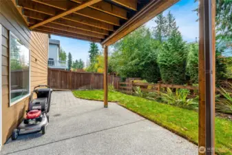 Private covered patio overlooking a serene backyard bordered by mature trees for added privacy. A perfect place to unwind or entertain year-round with room for outdoor seating and grilling.