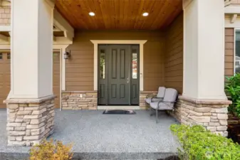Inviting front entry framed by stone accents and a covered porch, creating a warm first impression and a comfortable spot to sit and unwind.