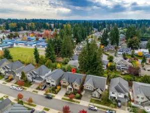 Expansive aerial view showcasing the home’s ideal location within a peaceful community surrounded by lush evergreens, parks, and nearby schools.